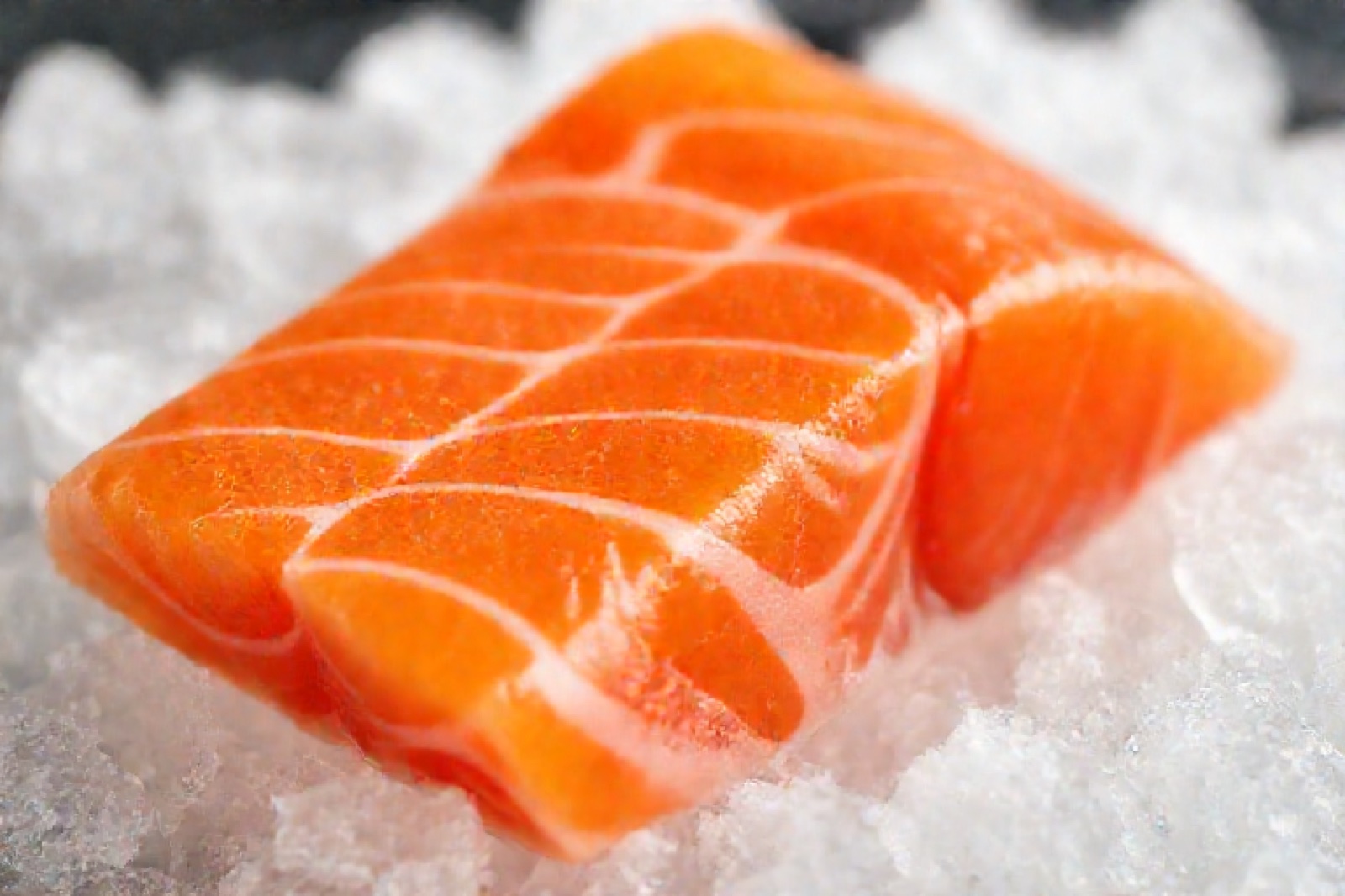 砕いた氷の上にのった、鮮やかなオレンジ色の生食用サーモンの柵
